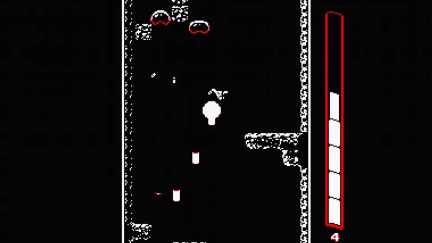 Игровой процесс с врагами и различными предметами, падающими вниз в Downwell