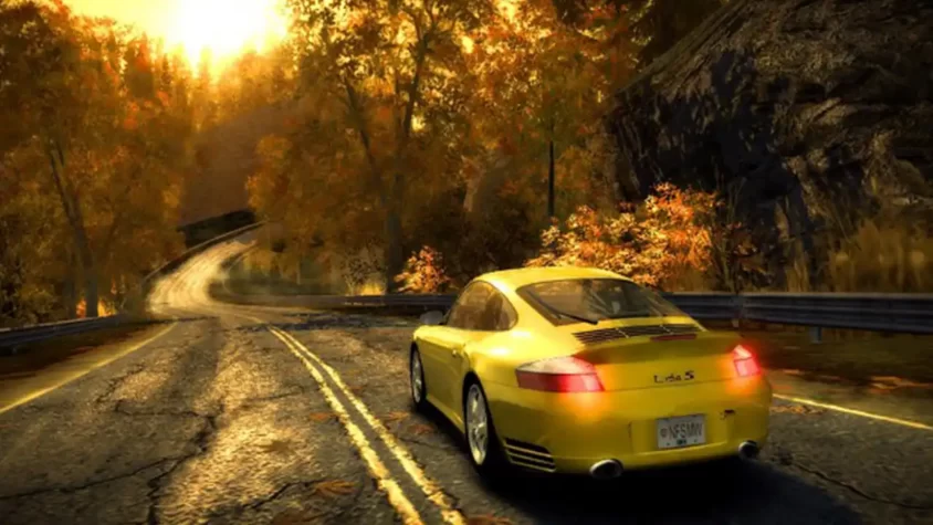 Жёлтая Porsche 911 на извилистой дороге на фоне осени