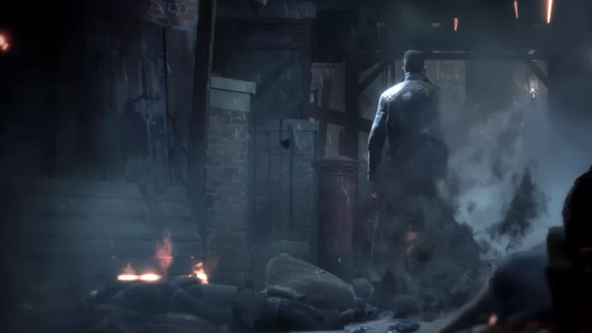 Главный герой игры Vampyr идет по темному и разрушенному переулку с дымом и огнем вокруг