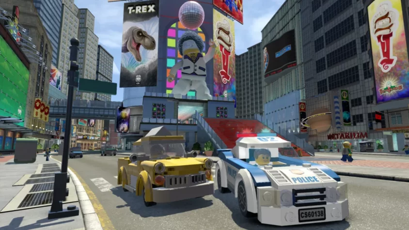 LEGO-полицейская машина и жёлтое авто на улицах LEGO-города с огромными рекламами и динозавром на баннере
