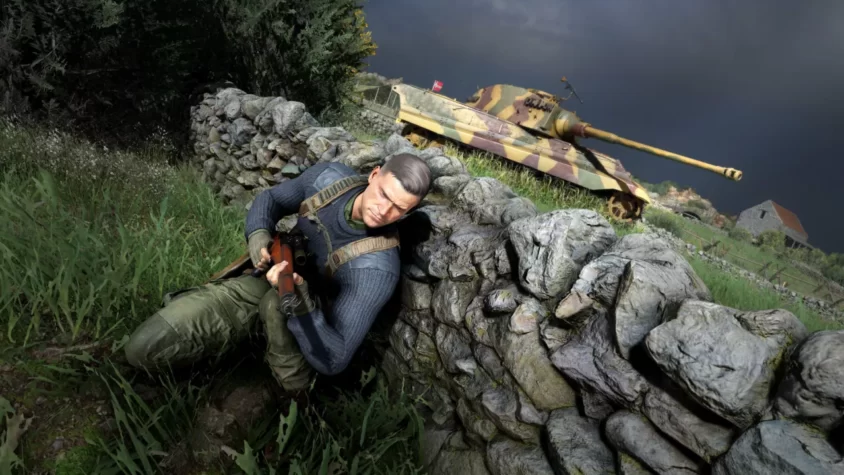 Игрок в Sniper Elite 5 прячется за каменной стеной с винтовкой, а за ним танк