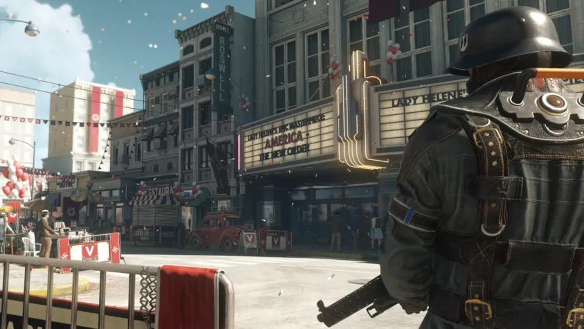 Персонаж в игре Wolfenstein II: The New Colossus стоит на улице, украшенной нацистской символикой, с флагами и баннерами, рекламирующими фильм